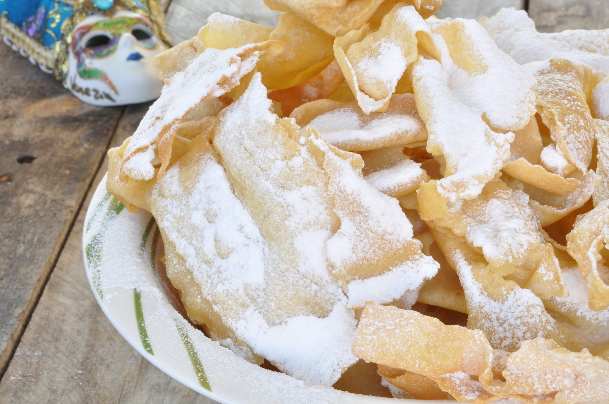 Chiacchiere Ricetta Bimby: un piatto di chiacchiere cosparse con zucchero a velo