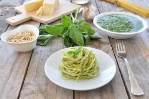 pesto bimby alla genovese: piatti di pasta condito col pesto e sullo sfondo la ciotola di pesto preparato con il bimby