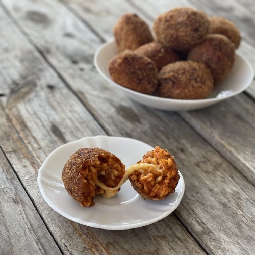 suppli mozzarella e pomodoro preparati con il bimby, disposti su un piatto e in primo piano un supplì aperto