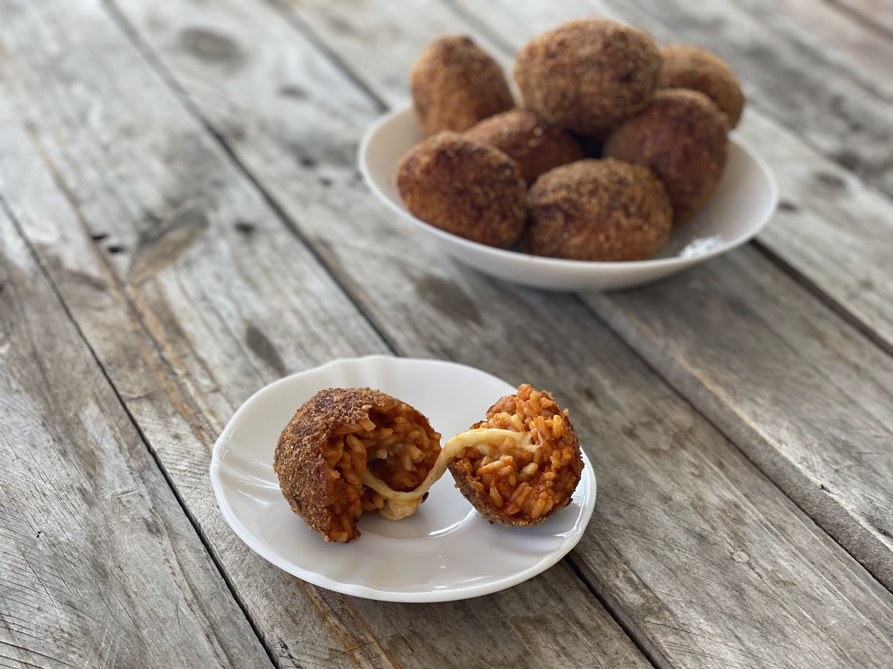 suppli mozzarella e pomodoro preparati con il bimby, disposti su un piatto e in primo piano un supplì aperto